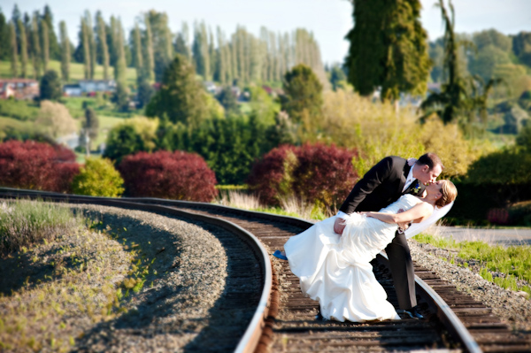 Groom dipping bride for a kiss while standing on railroad track in the beautiful countryside - photo by Portland wedding photographer Barbie Hull 